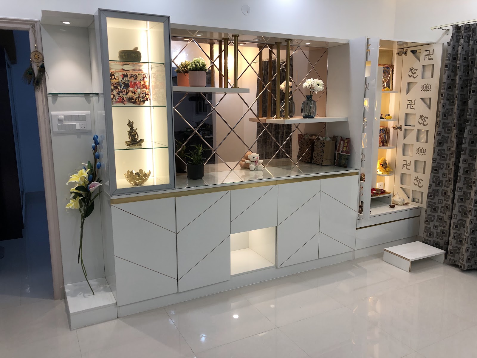 Living/entrance divider unit combining a glass-front curio display case, a diamond mirror-panelled console with a brass rod screen