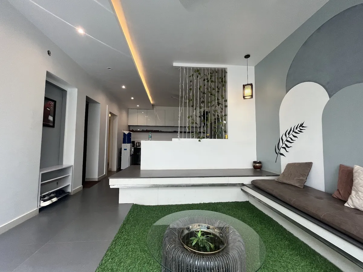 Sunken living area with a built-in bench under a painted grey-and-white double-arch mural carrying a black fern motif
