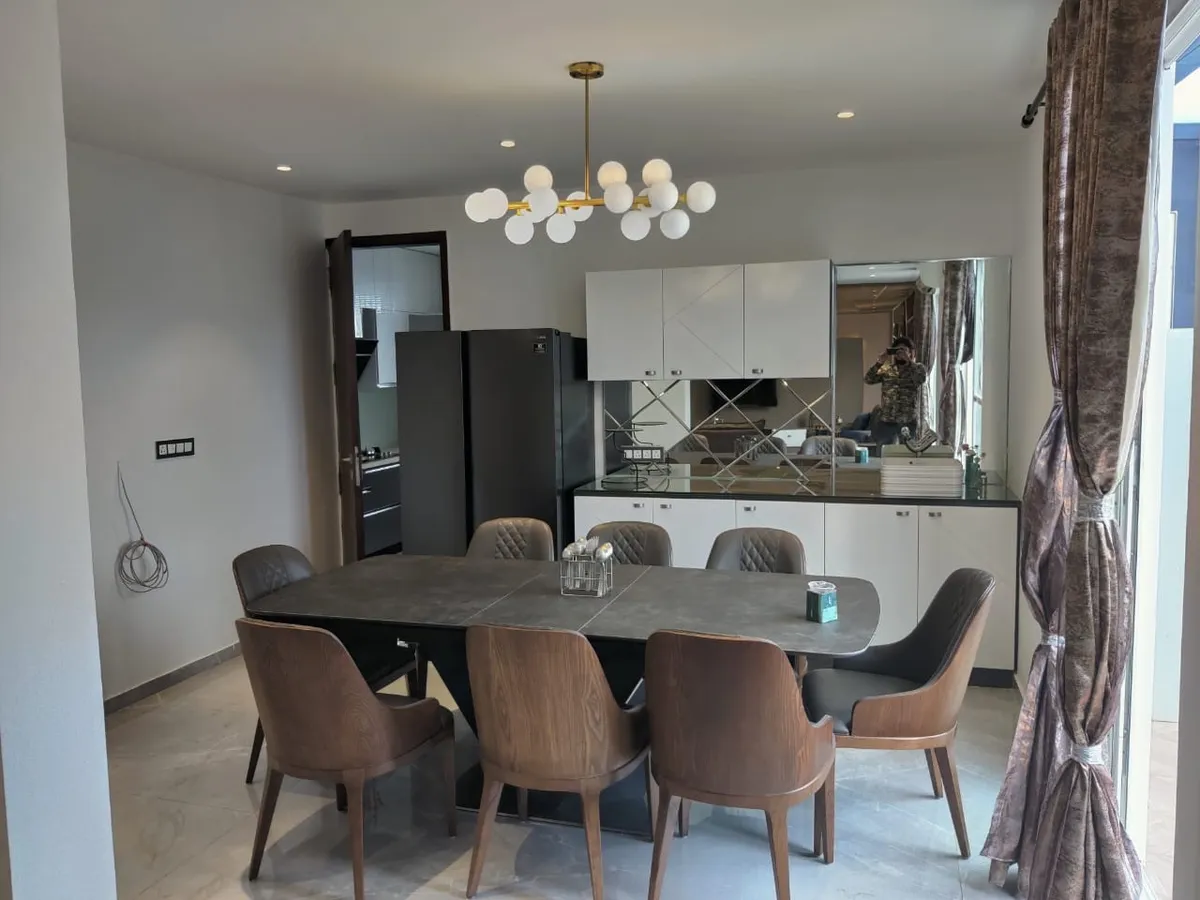 Eight-seater grey sintered-stone dining table under a brass sputnik globe chandelier