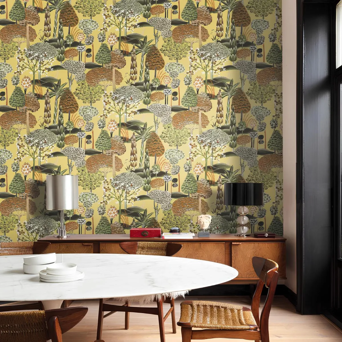 Dining corner where a chartreuse woodland-print wallpaper runs full height behind a walnut mid-century credenza topped with a steel and a black lampshade