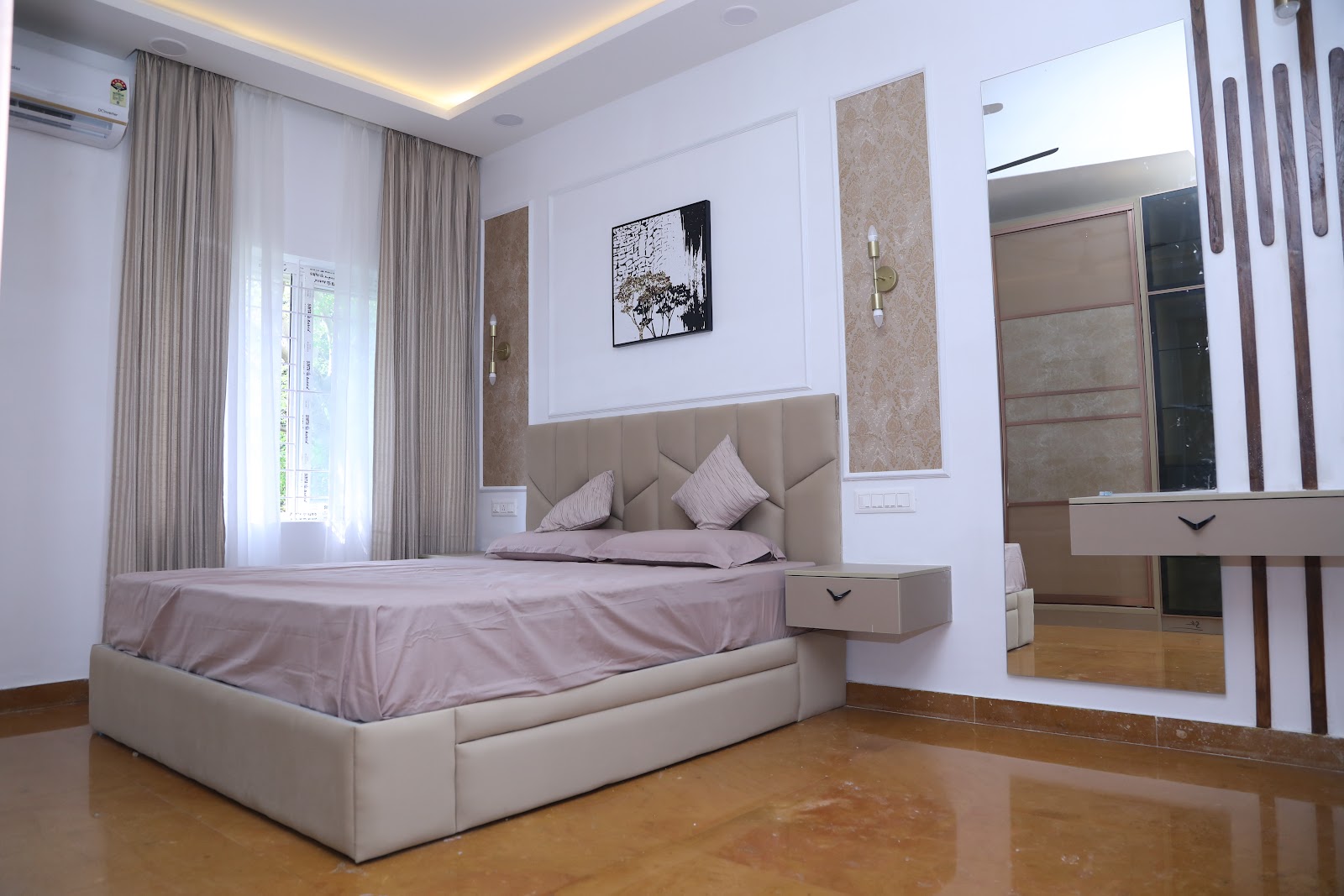 Master bedroom with a geometric channel-stitched taupe headboard, wall panelling with damask wallpaper insets and brass sconces, a floating nightstand