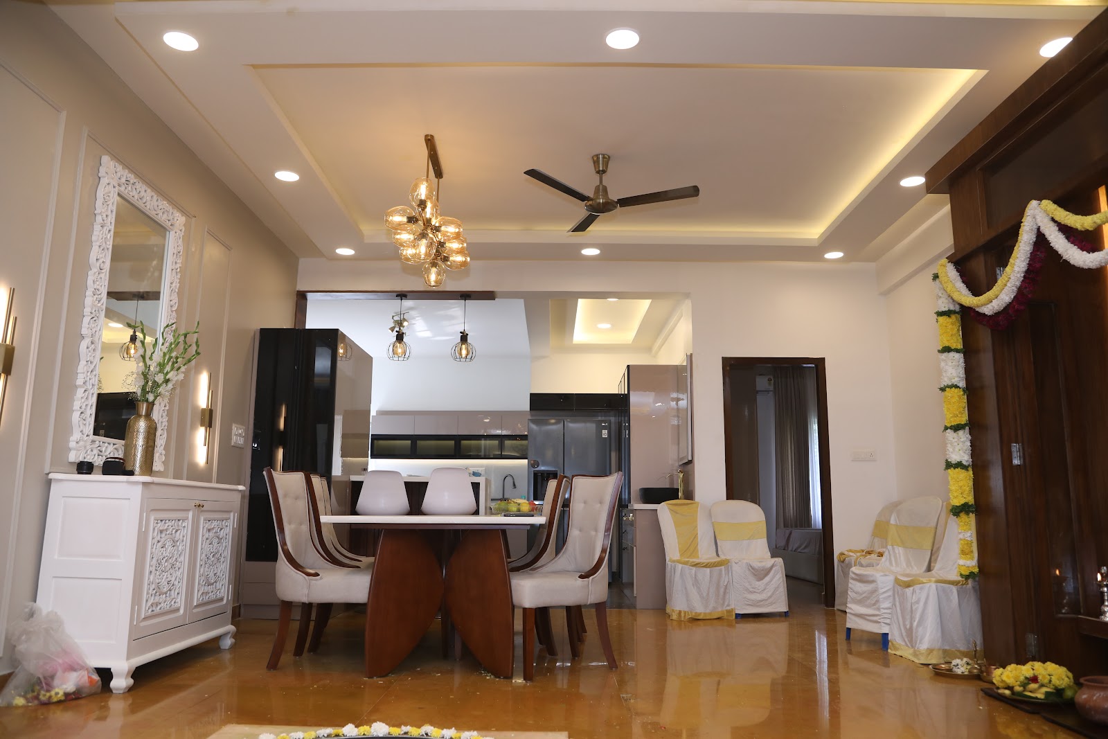 Open dining area with a six-seater wood dining table and cluster pendant light beneath a cove-lit tray ceiling