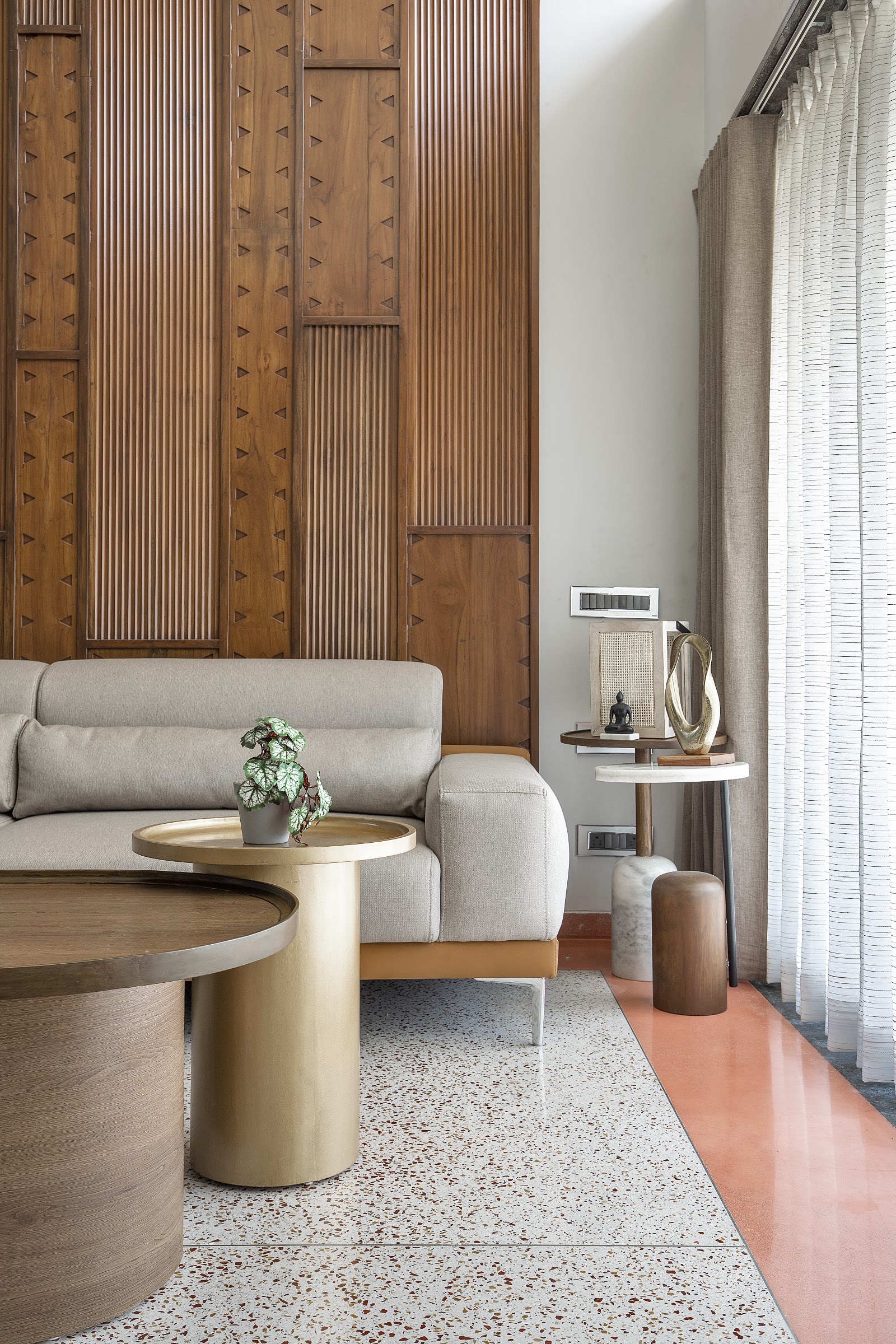 Living room with a hand-carved teak triangular-fluted feature wall, terrazzo flooring bordered in coral