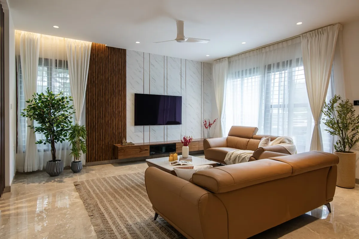 Tan leather recliner sofas face a marble-slab TV wall scored with vertical groove lines