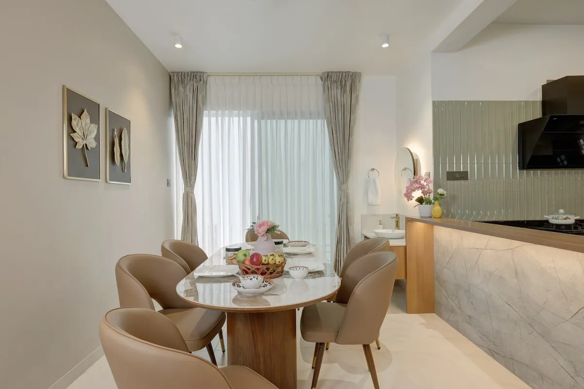 Dining nook with a marble-top oval table and six tan leather chairs in front of sheer curtained windows
