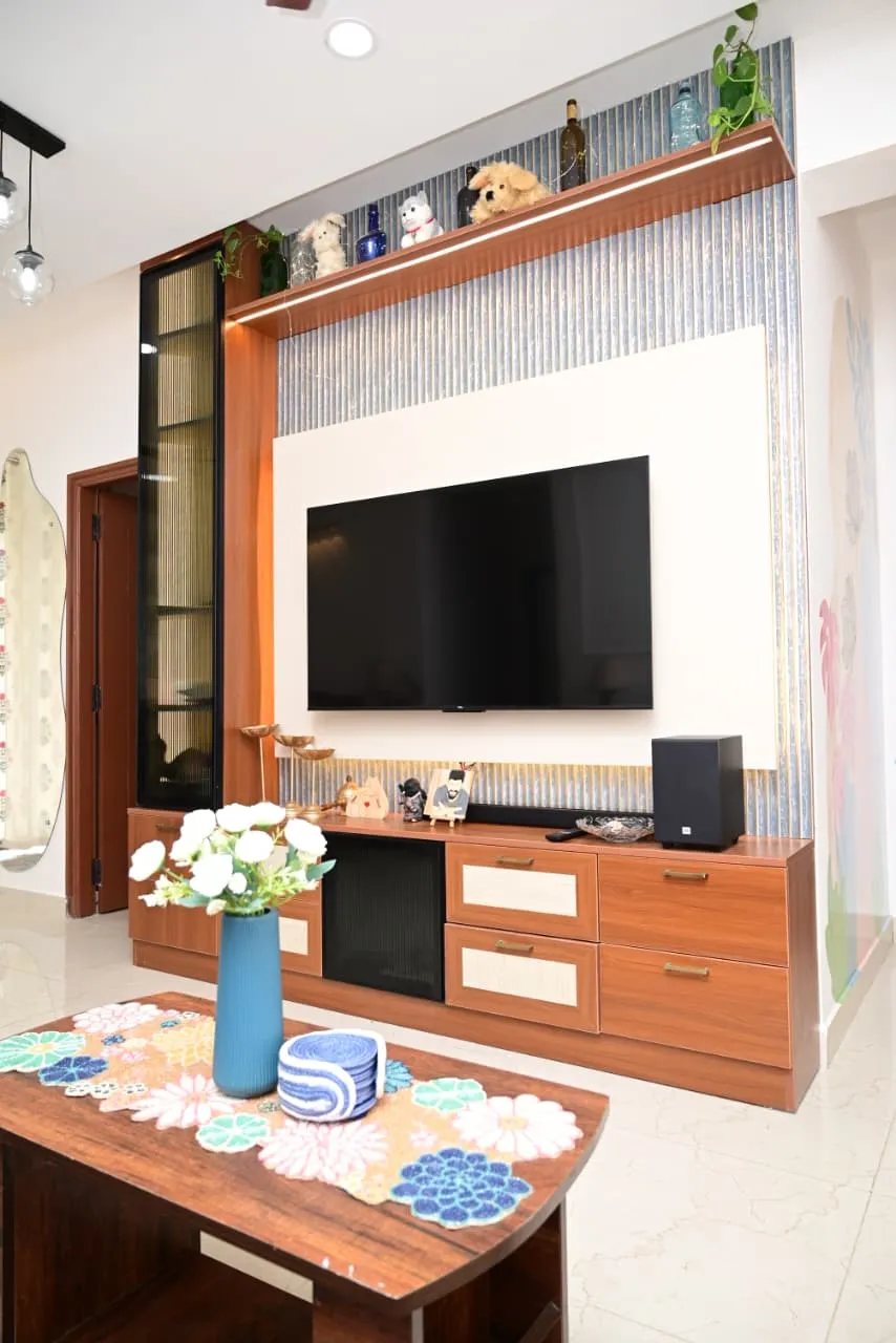 Teak-laminate TV unit with cane-webbing drawer fronts, its white TV back-panel set into blue-grey fluted panelling