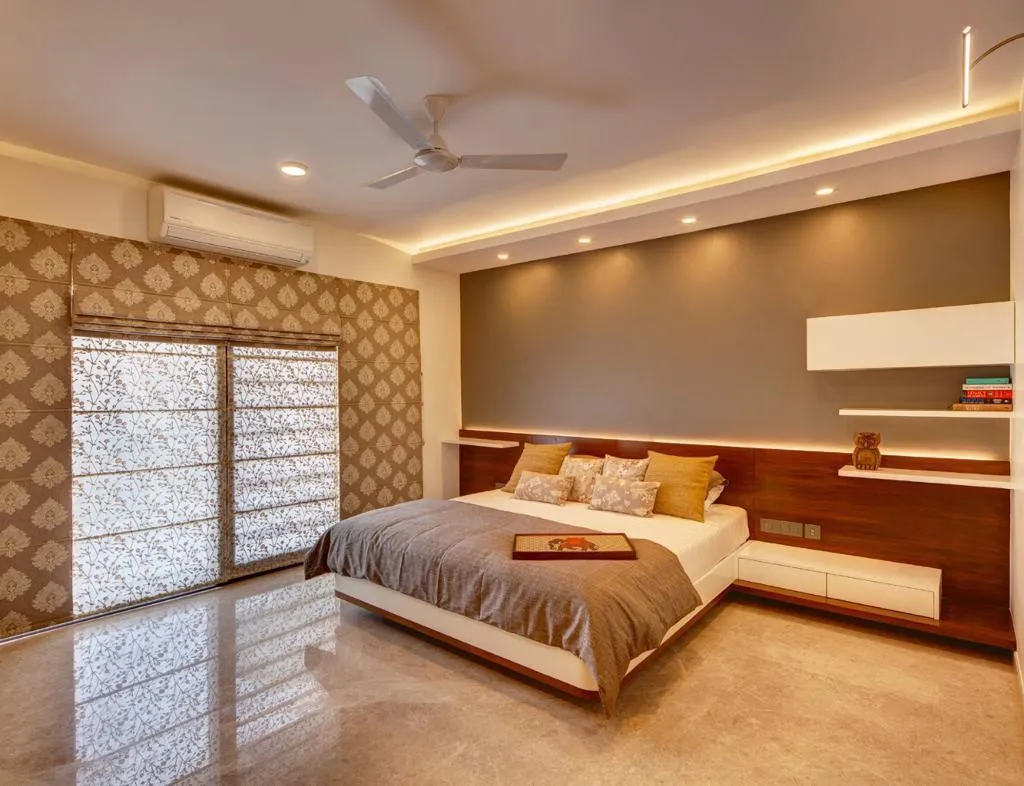 Master bedroom with a full-width wood headboard wall with a floating nightstand and open display shelf, a cove-lit ceiling