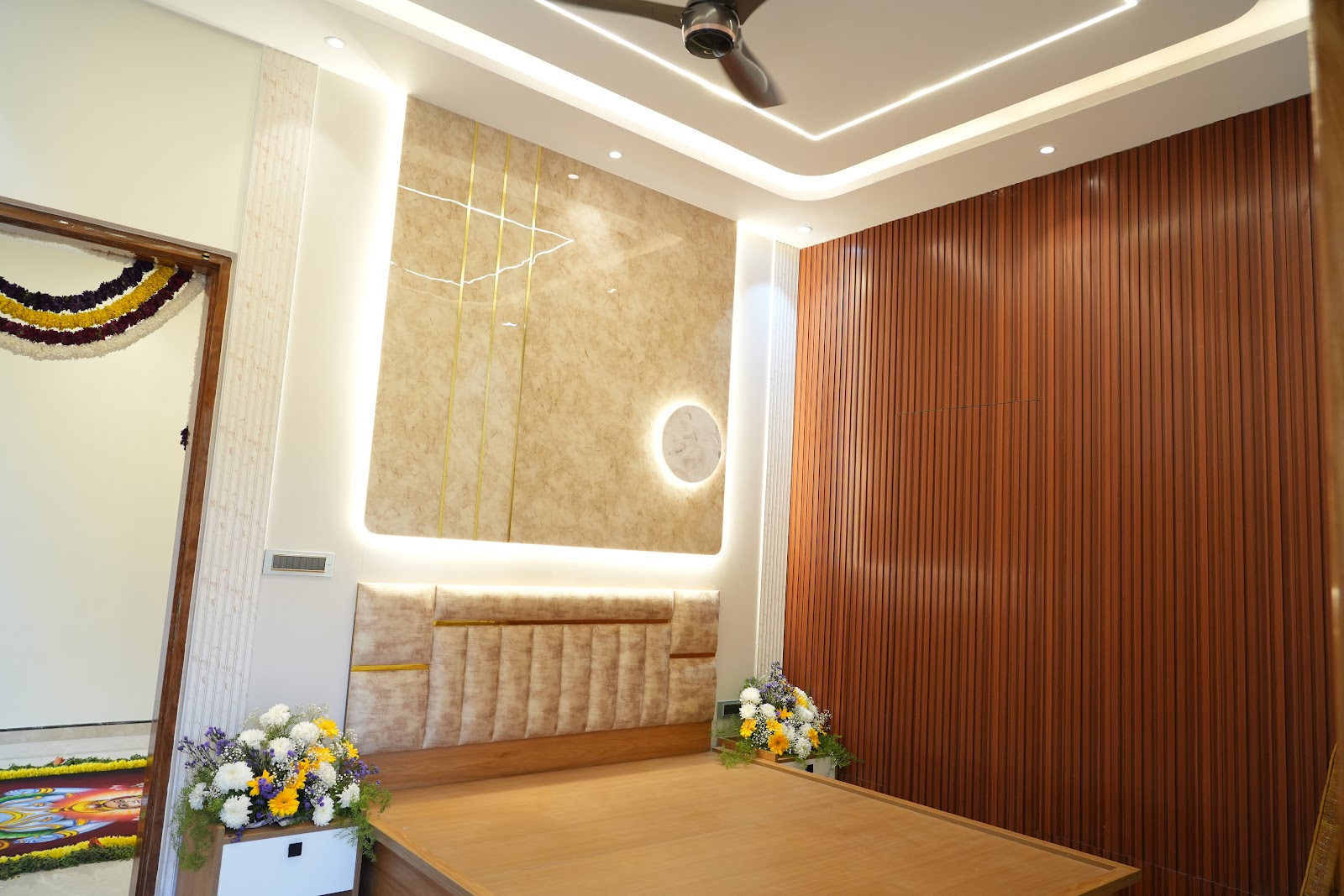 Bedroom with a backlit marble-and-brass inlay feature wall behind a channel-tufted headboard, and a fluted wood-panelled side wall