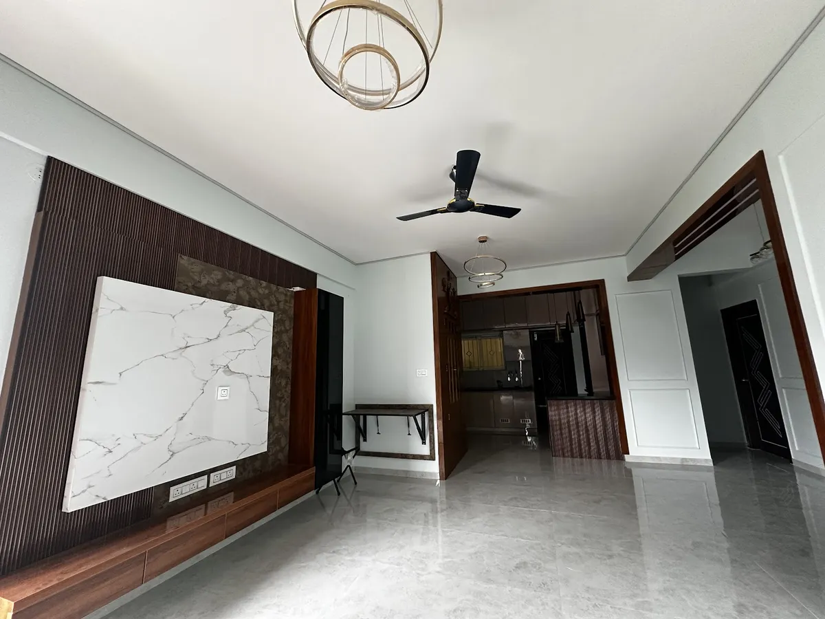 Empty handed-over living room where a dark fluted TV wall carries a white marble slab panel over a low walnut console