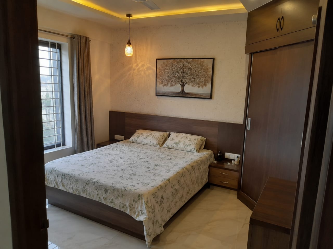Bedroom with a dark wood platform bed and matching sliding wardrobe, a framed tree painting above the headboard, a cove-lit ceiling