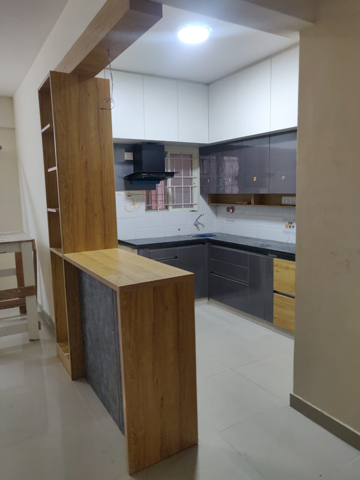L-shaped modular kitchen with high-gloss charcoal-grey shutters and black granite counters