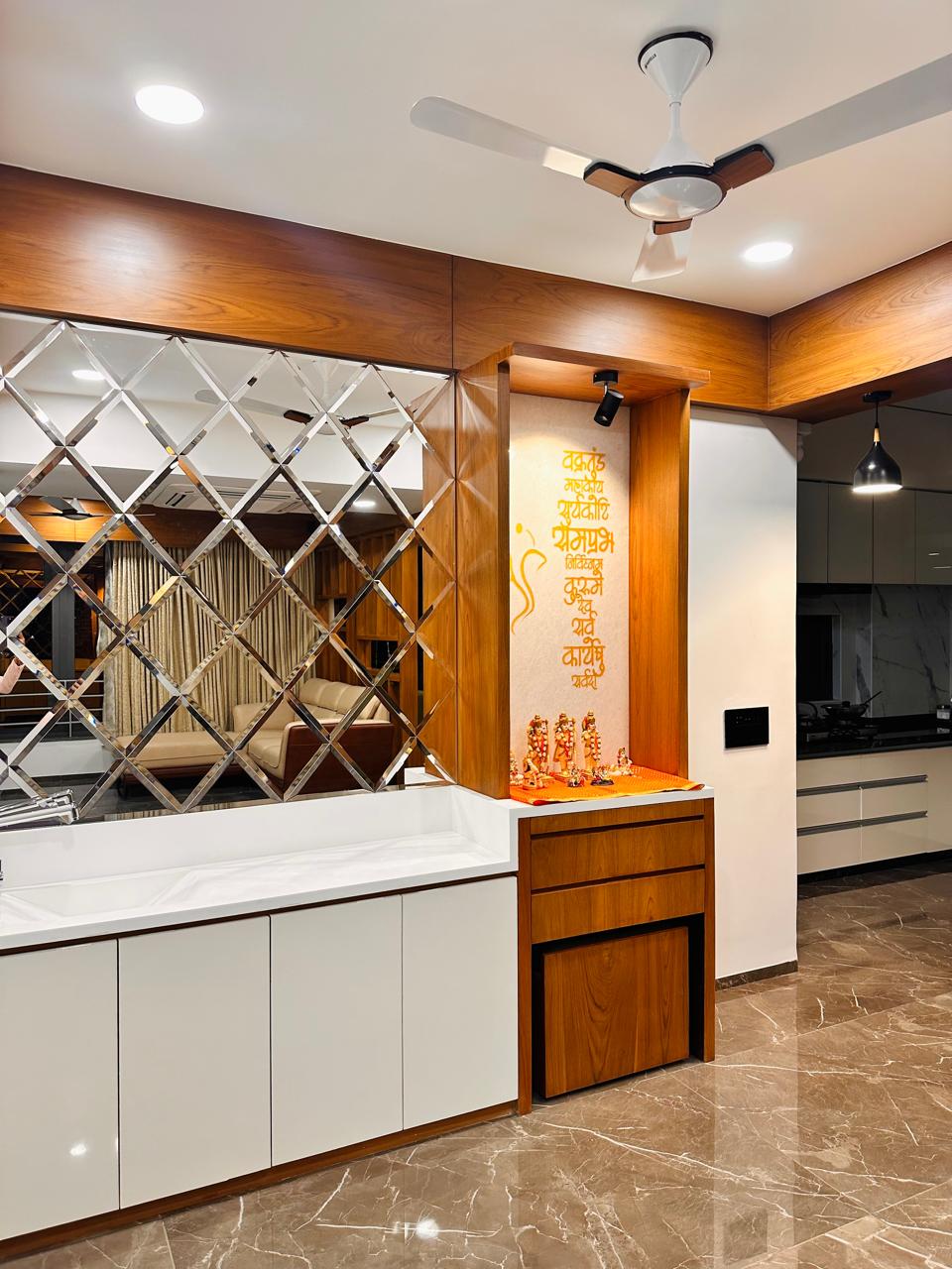 Pooja niche built into a wood-framed alcove with Sanskrit shloka wall art and deity idols on an orange cloth