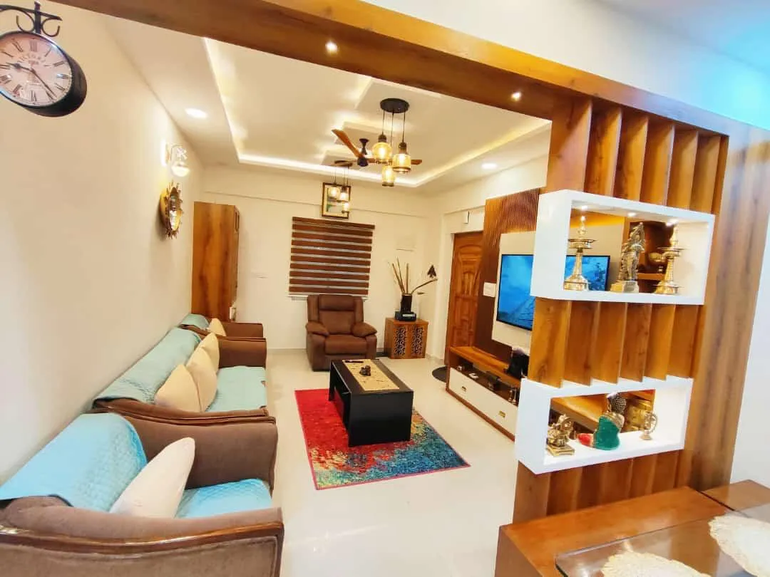 A living room with a coffered false ceiling and cluster pendant lights, teal-cushioned sofas around a red-patterned rug