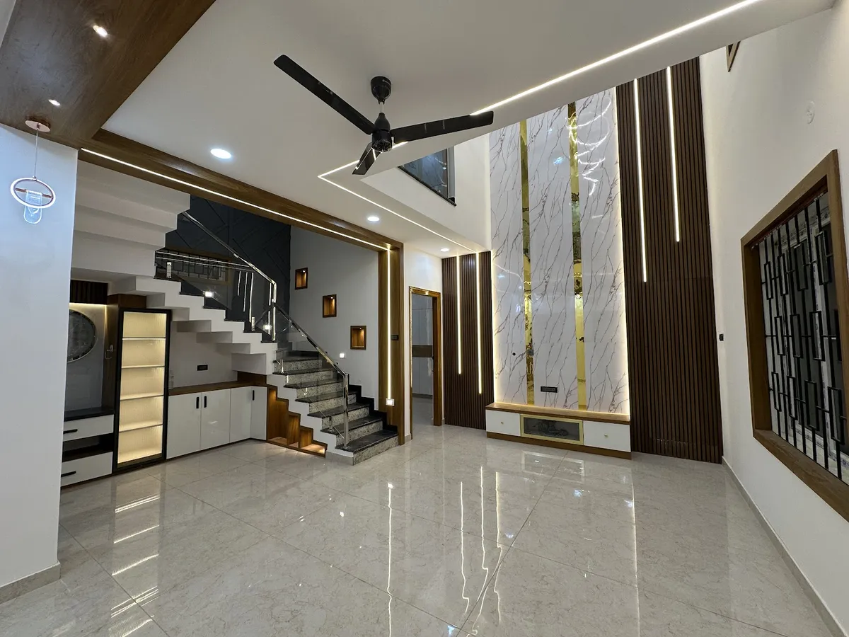 A double-height entrance hall with a granite staircase behind a glass railing, a book-matched marble feature wall with gold inlay strips