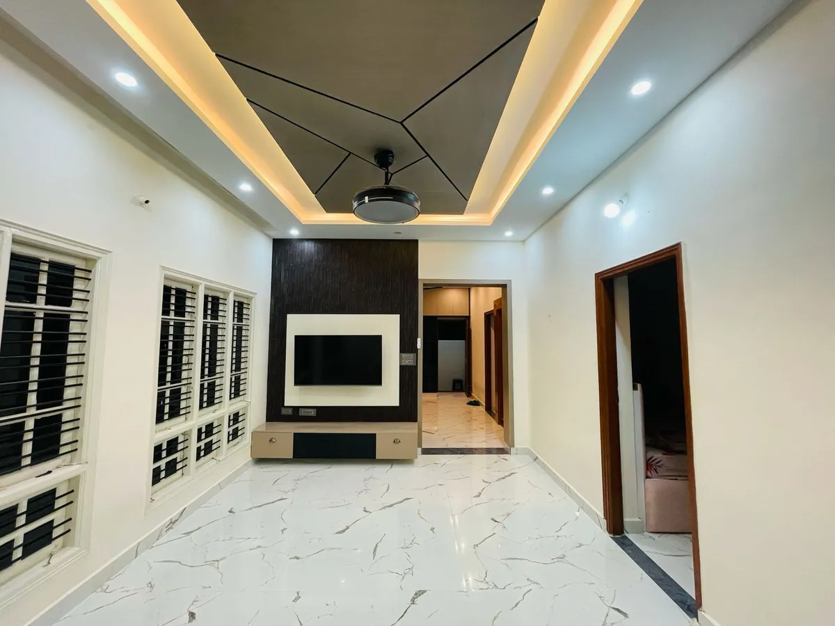 Empty hall with a dark wood-grain TV panel framed in white gloss above a two-drawer floating console