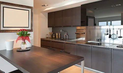 Small low-resolution shot of a wenge-and-stainless galley kitchen with a full-height steel splashback