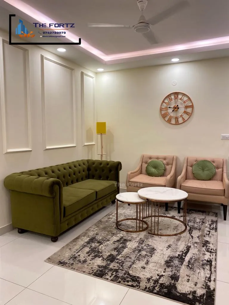 Olive velvet Chesterfield facing two blush tufted armchairs with round green bolsters