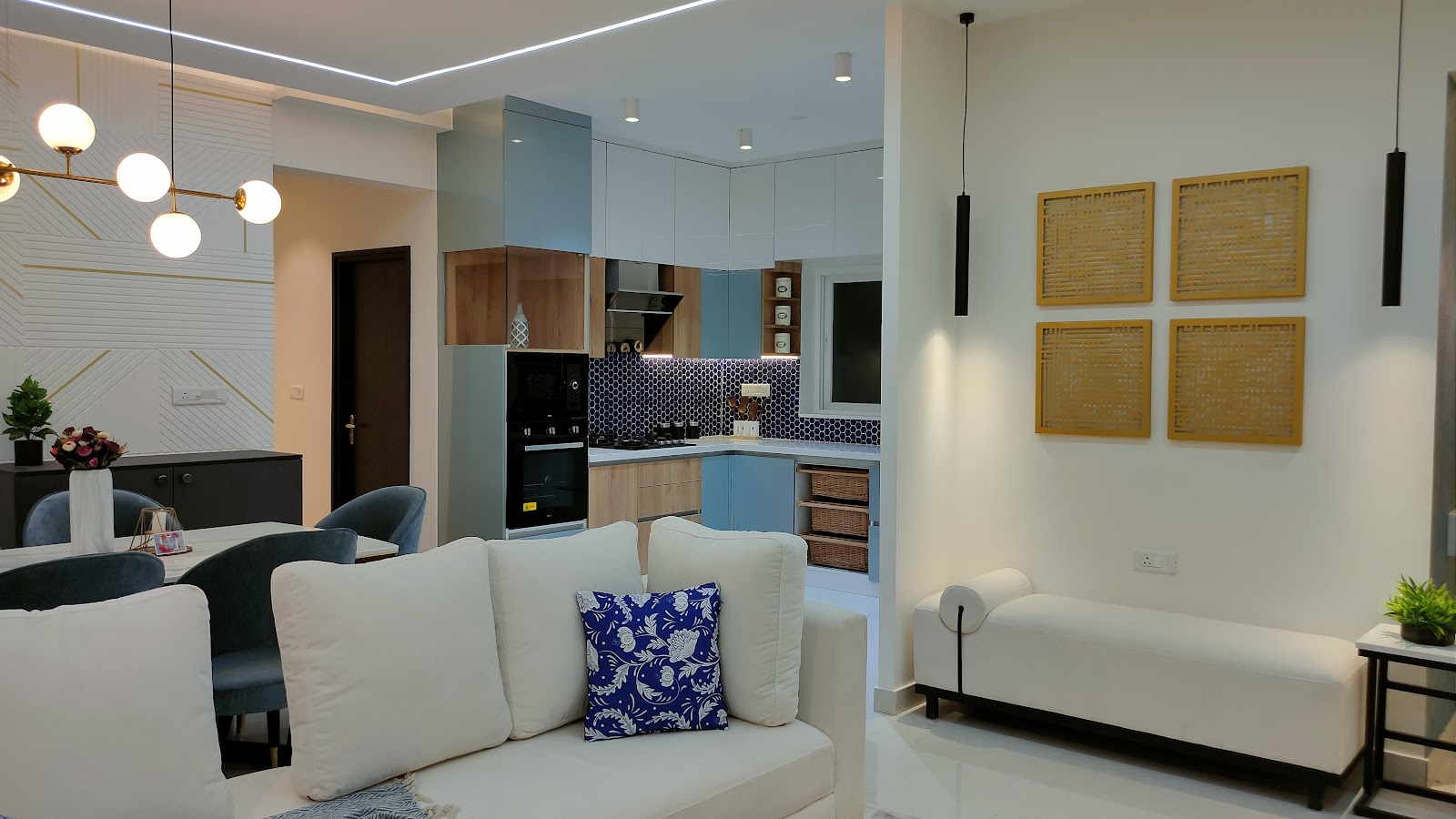 Open-plan living-dining-kitchen with a white sofa and chaise lounge in the foreground, a globe chandelier over the dining table