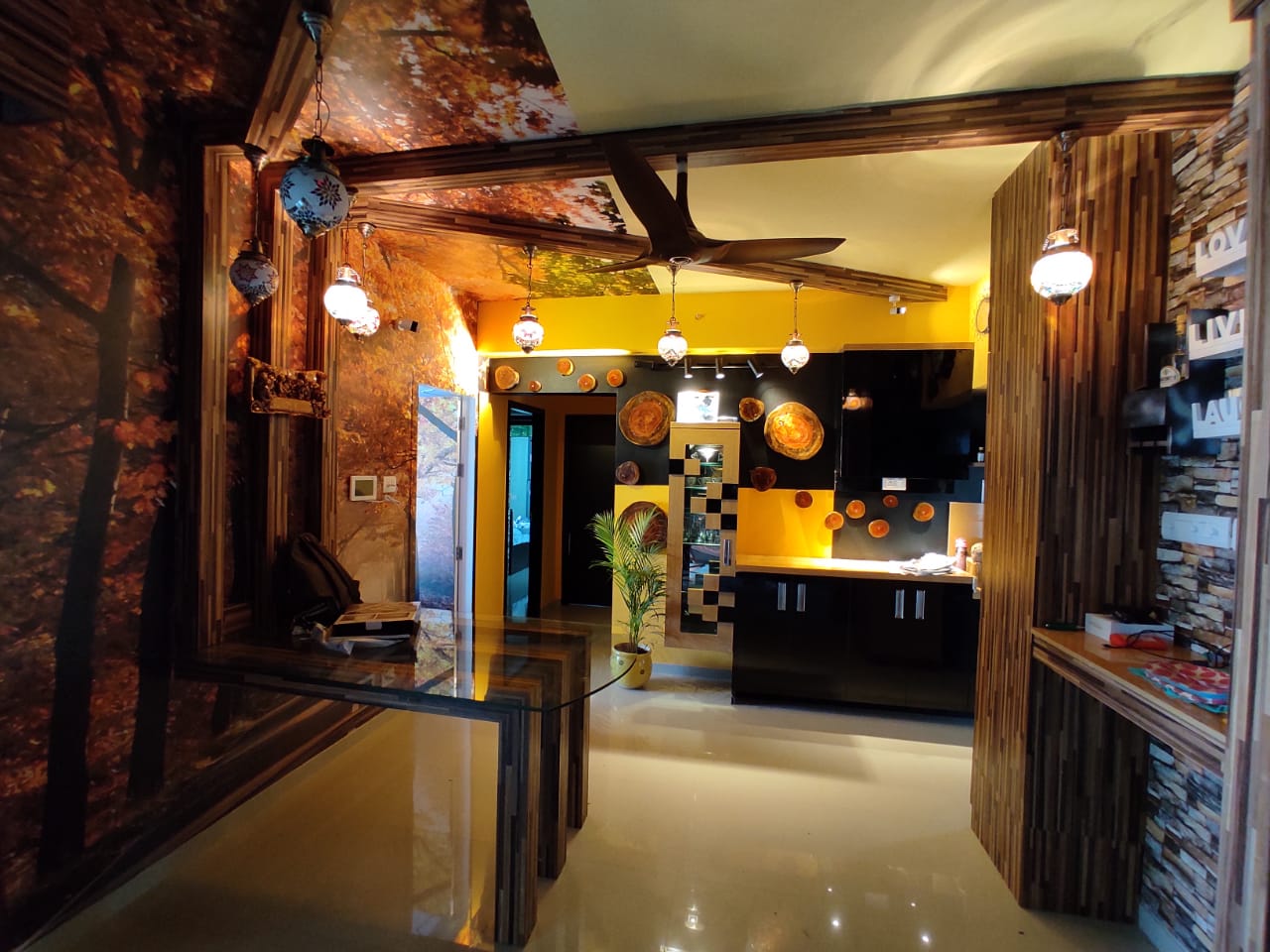 Eclectic dining-to-kitchen passage with a forest-mural ceiling, mosaic Moroccan pendant lanterns, a glass-top wood dining table