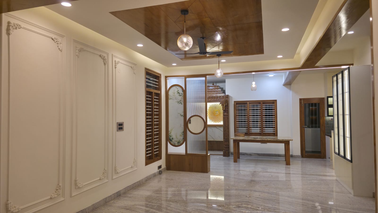 Empty entrance hall with ornate white wall-moulding panels, a wood-panelled ceiling with pendant lights, a fluted-glass partition screen