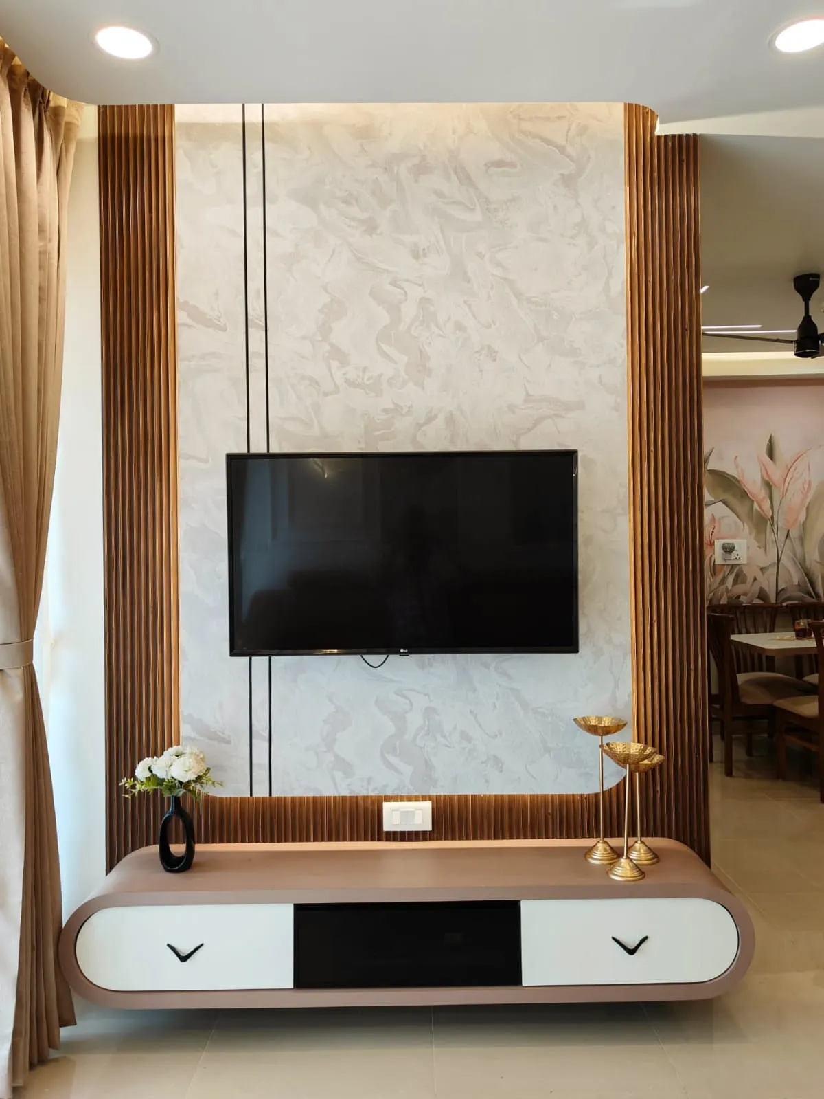 Living room TV wall framed in fluted wood-and-brass panelling around a marble-effect feature wall
