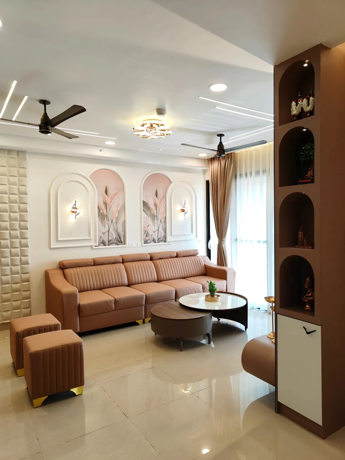 Tan channel-tufted leather sofa under twin arched mouldings framing blush botanical panels
