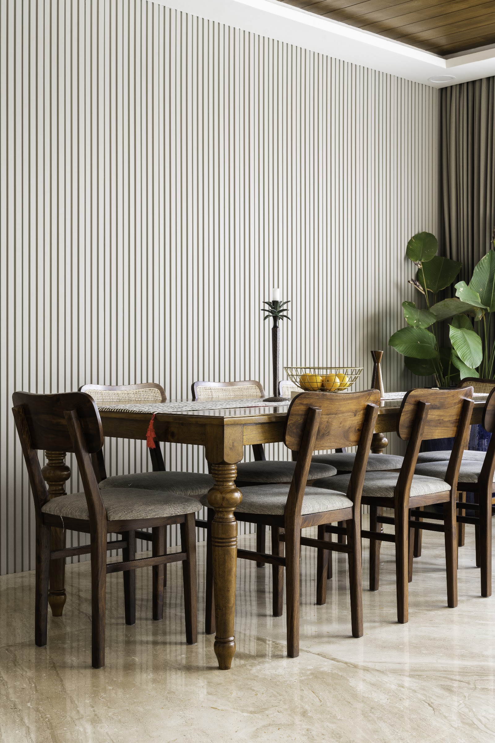 Dining room with a fluted vertical panel accent wall, a wood ceiling, a turned-leg wood dining table seating eight in a mix of cane-back and solid wood chairs