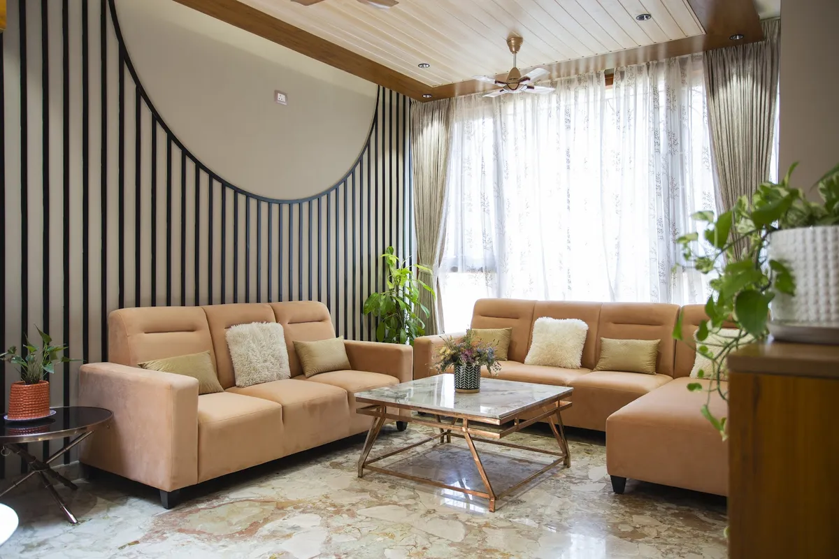 Peach velvet sofas facing a marble-top brass coffee table against a wall of slim black fins framing a big circular reveal