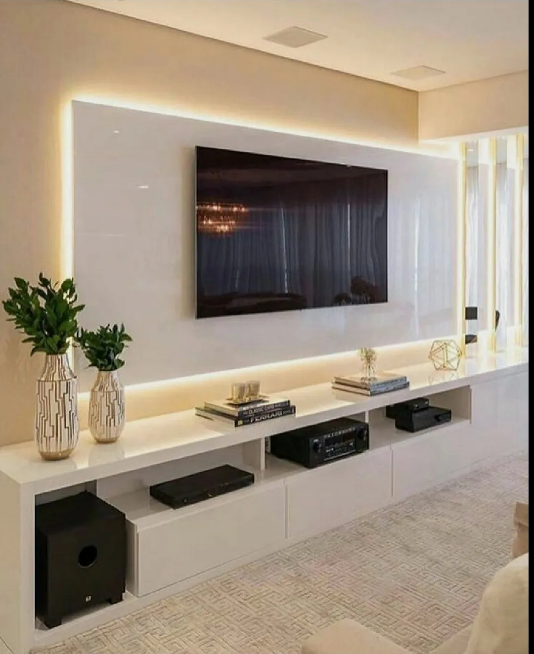 A white high-gloss TV panel floating off a cream wall with a warm LED halo running right around it