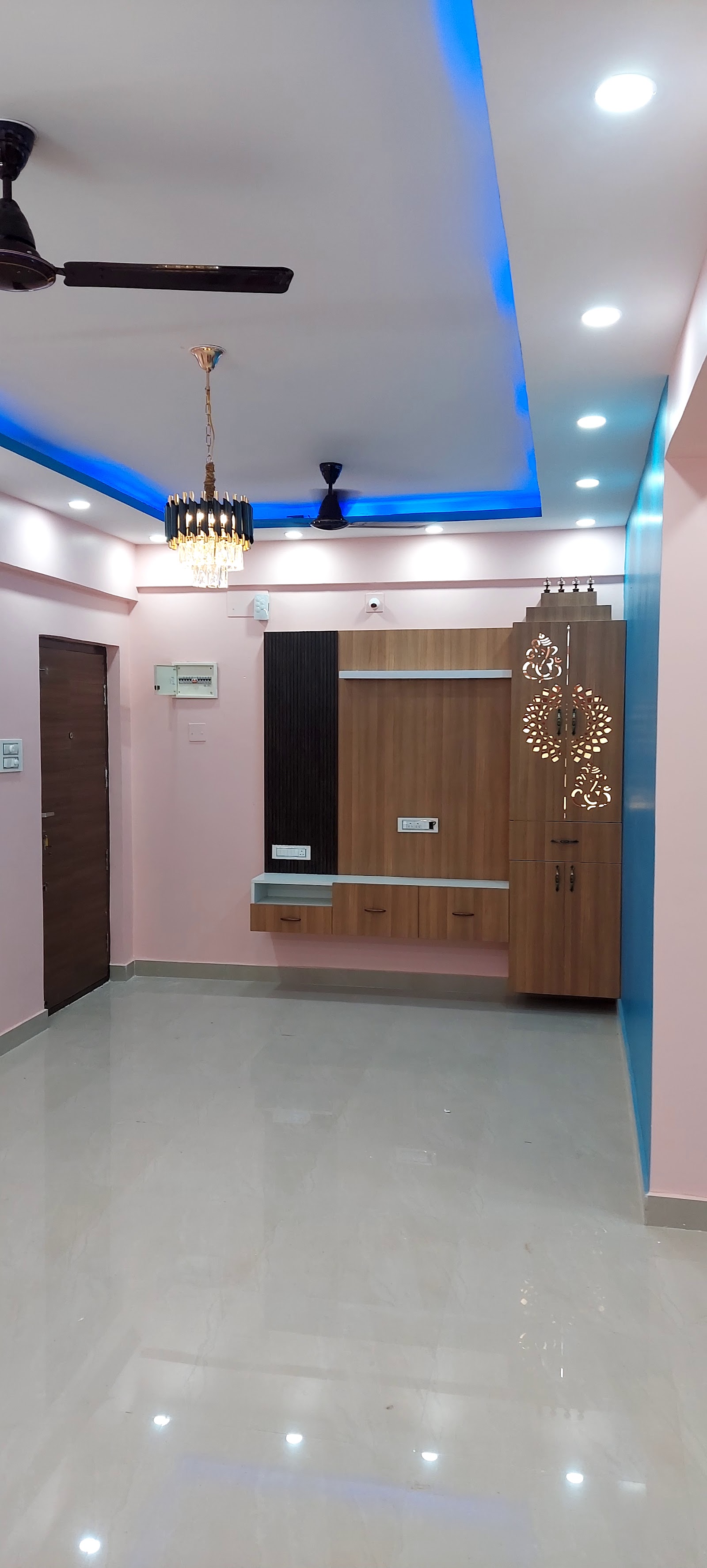 Empty living room entryway with a rose-pink and blue color-blocked wall, a blue LED cove ceiling, a crystal pendant light