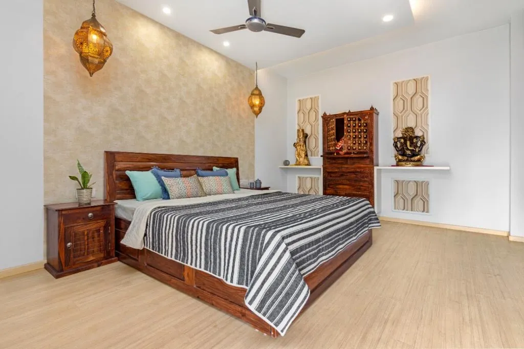 Traditional wood bed with a black-and-white striped throw, moroccan-style filigree pendant lanterns, a textured wallpaper headwall