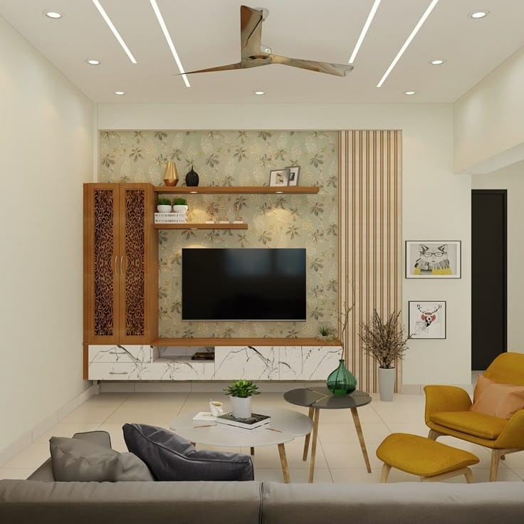Render of a living room TV wall with floral wallpaper, a marble-effect base unit, and a mustard-yellow accent armchair beside a grey sofa.