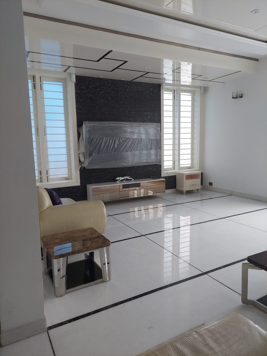 Living room with a glossy stepped ceiling, a black textured-stone TV wall, and a mirrored glass TV console