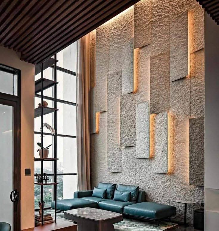 Double-height living room with a staggered raw-stone feature wall lit by vertical backlit coves, a dark wood-slat ceiling