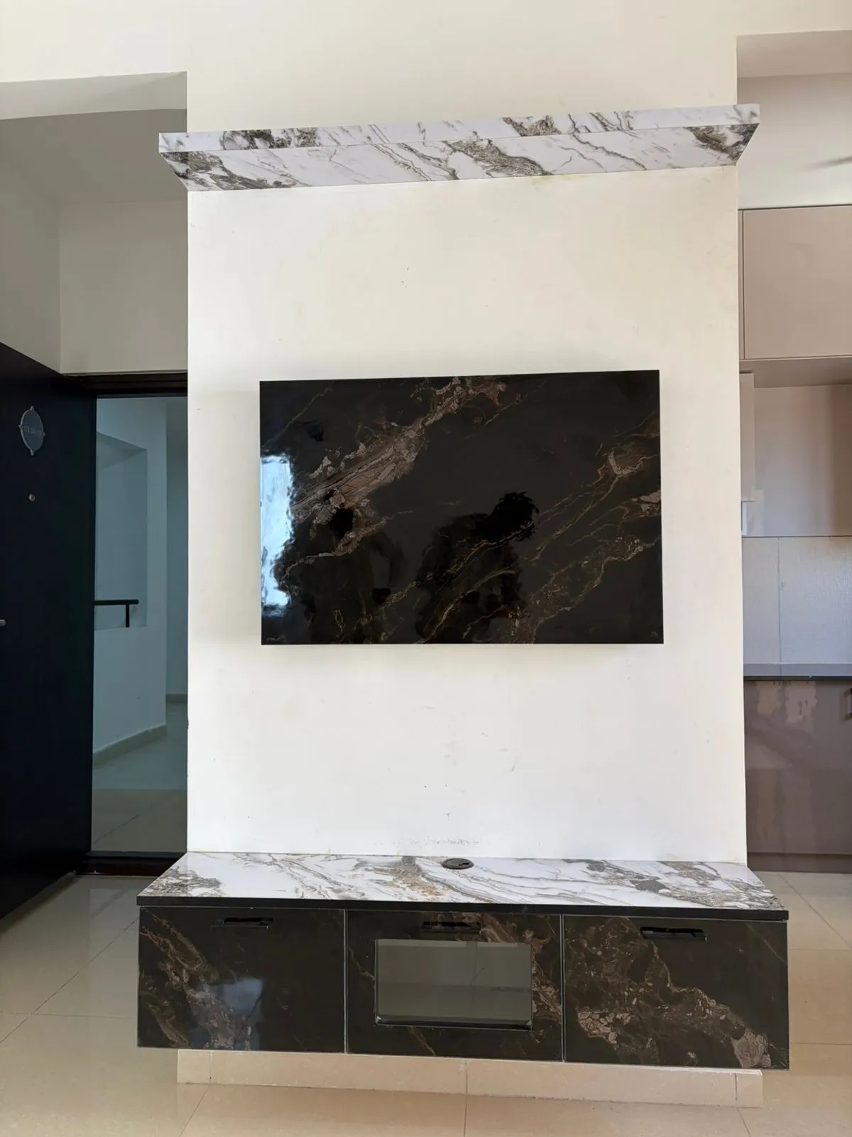 Floating TV console wall in bookmatched grey-and-white marble slab cladding with a dark marble-fronted floating storage unit below