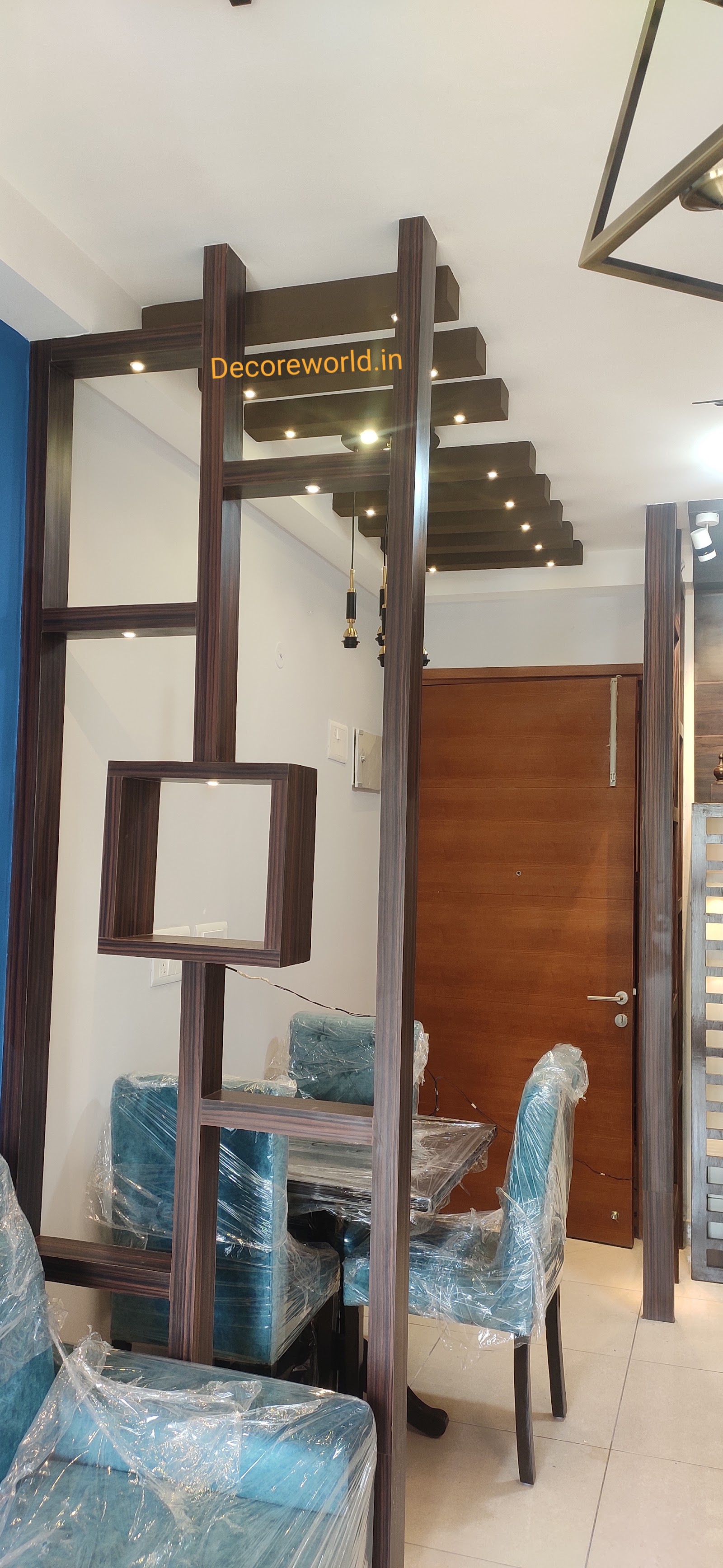 Dining area with a fretwork wood room divider featuring lit display cubes, a stepped wood-slat ceiling with pendant lights