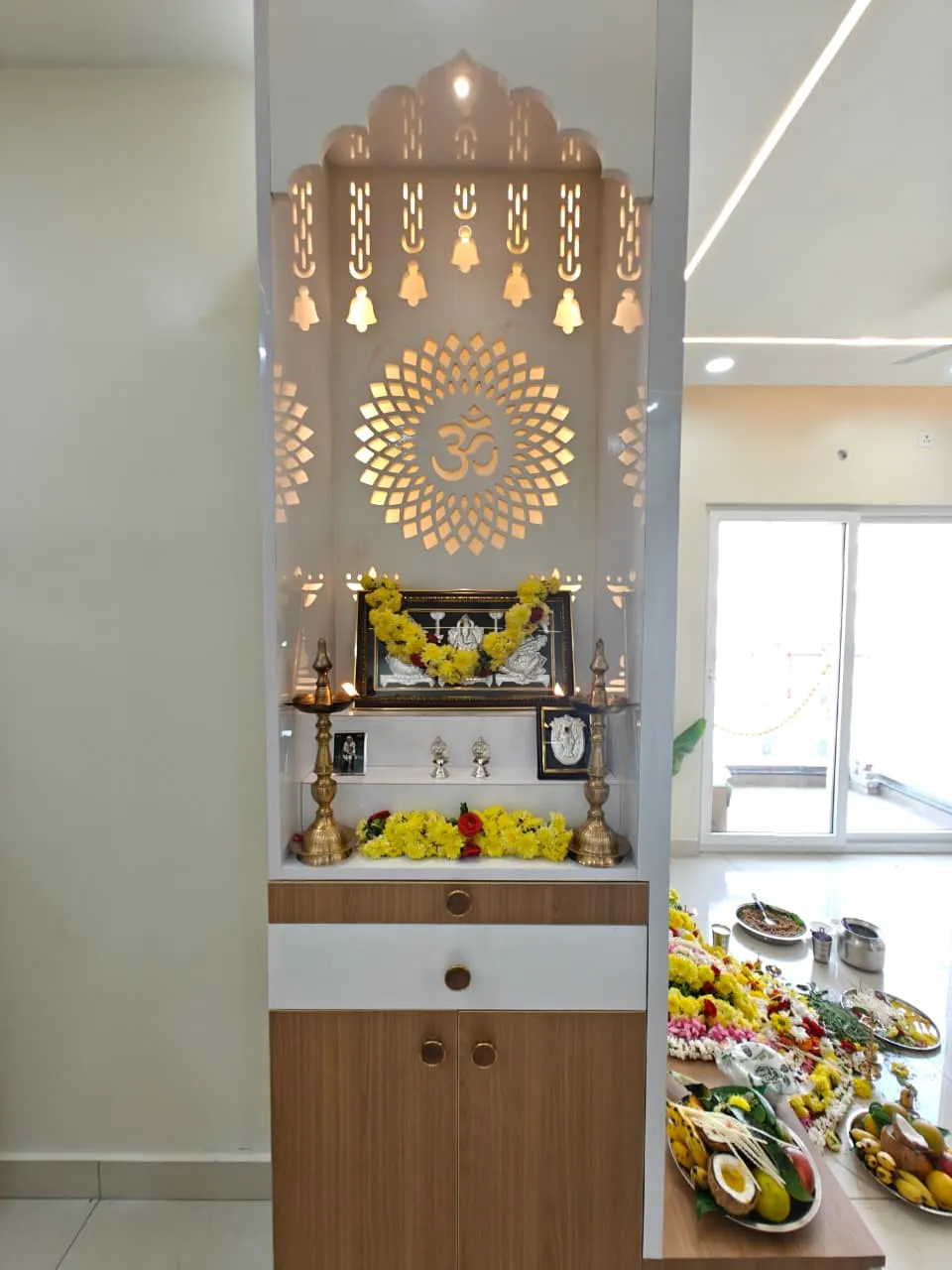 Freestanding pooja unit with a temple-arch top: backlit CNC-cut hanging bells and an Om mandala in white