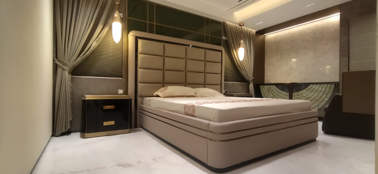 Luxury bedroom with a tall champagne tufted-leather bed and matching upholstered base, a black-and-gold nightstand