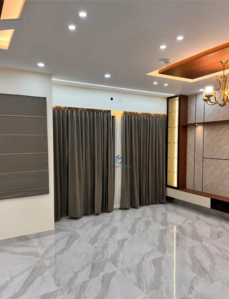 Empty living room with floor-to-ceiling brown curtains, a marble-clad TV feature wall with a lit glass display niche, and a small crystal chandelier