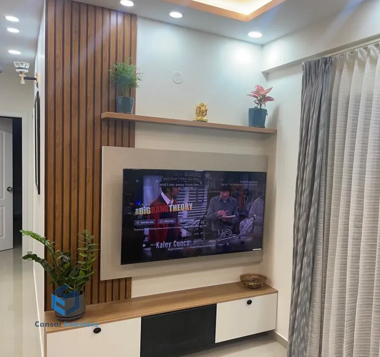 Living room TV wall with a fluted wood panel accent strip, a floating wood shelf styled with plants and a small idol, and a two-tone TV unit below.