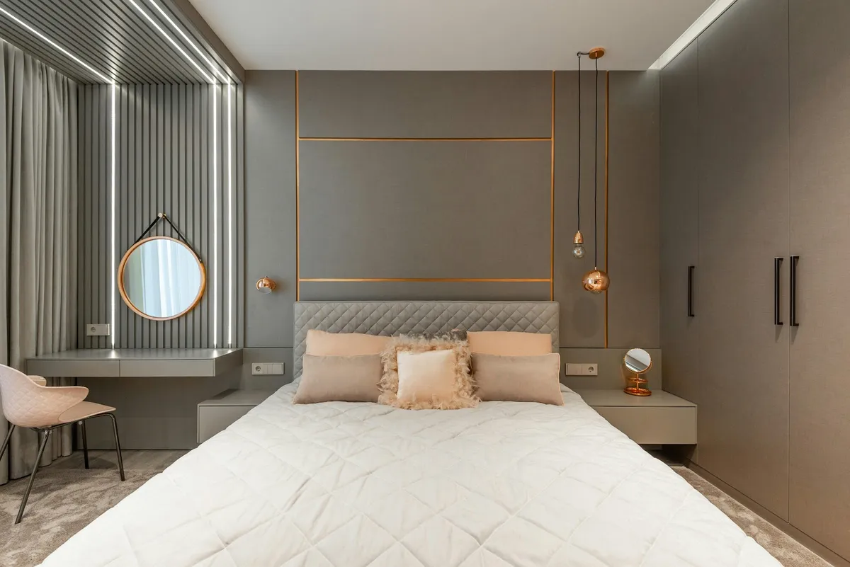 Grey upholstered bed wall inlaid with slim rose-gold lines, twin copper globe pendants dropped on cords
