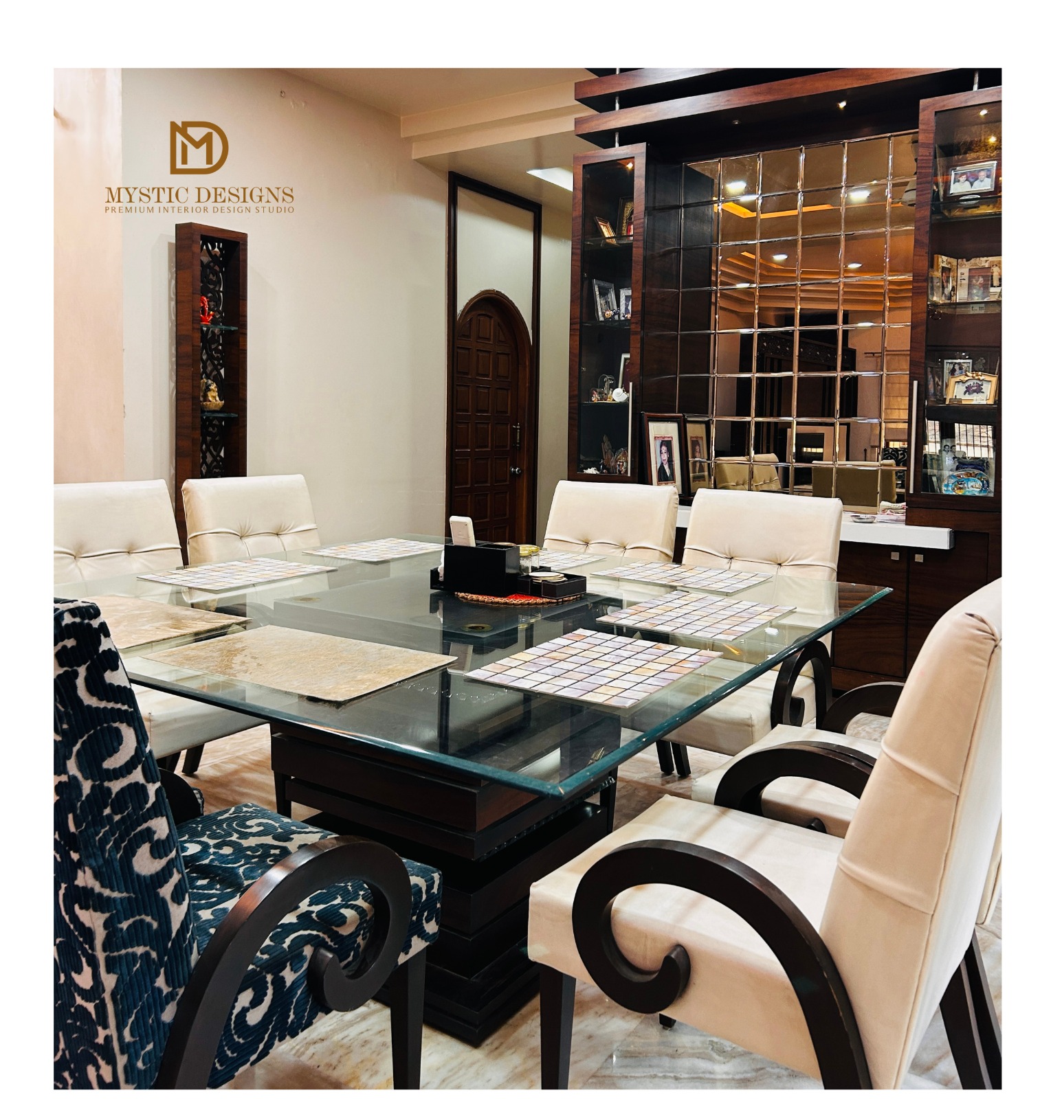 Dining room with a square glass-top table, ornate scroll-arm chairs in cream and teal-patterned upholstery