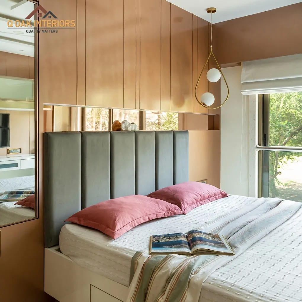 Bedroom with a vertical wood-panelled wall, a channel-tufted grey headboard, dusty pink pillows