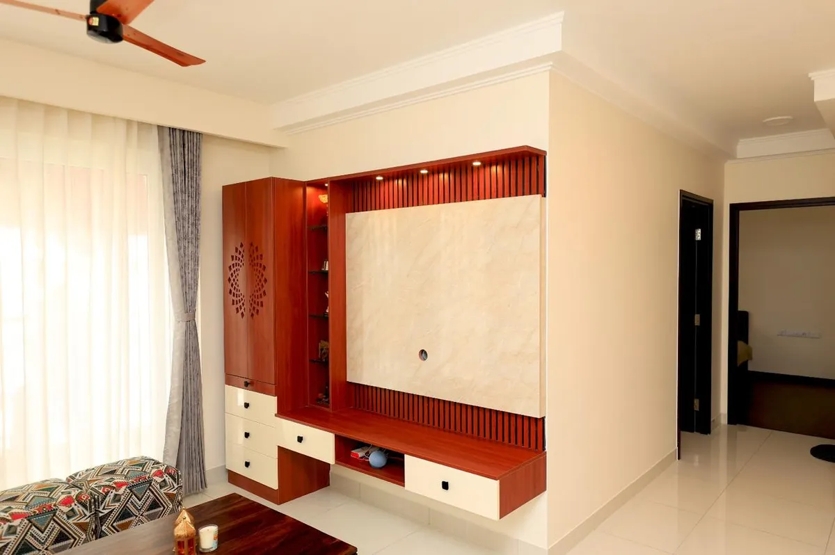 Living-room TV wall in cherry-red veneer with a fluted batten surround, a beige marble slab back panel and cream drawer fronts