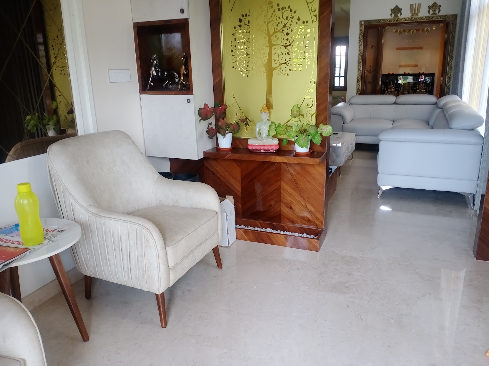 Living room with a wood console divider featuring an etched golden tree mirror panel, a cream tufted armchair