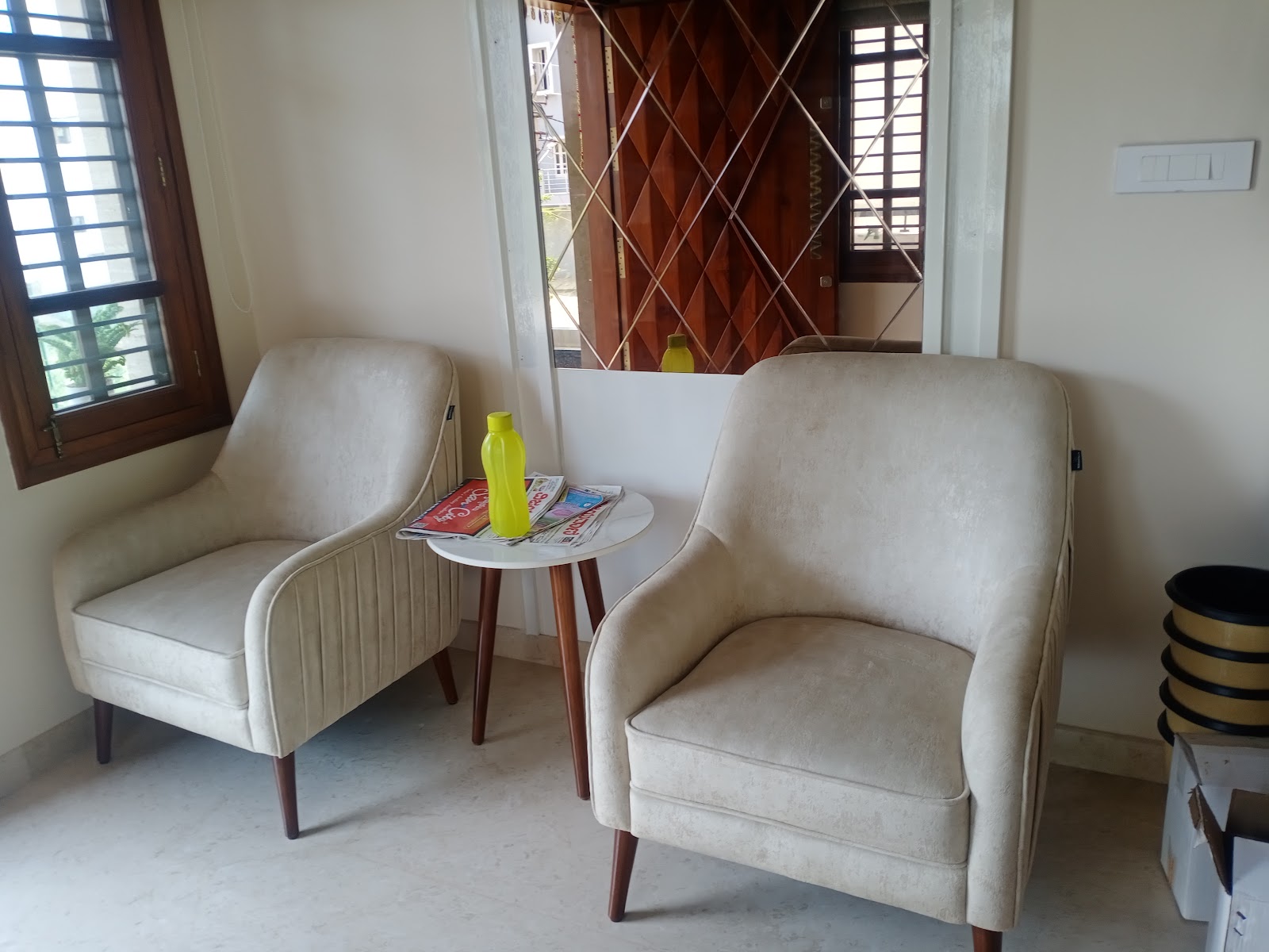 Small seating nook with two cream velvet-look armchairs and a round marble-top side table