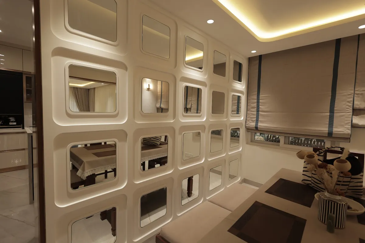 Dining nook divided by a striking grid-patterned mirror partition wall under a cove-lit ceiling
