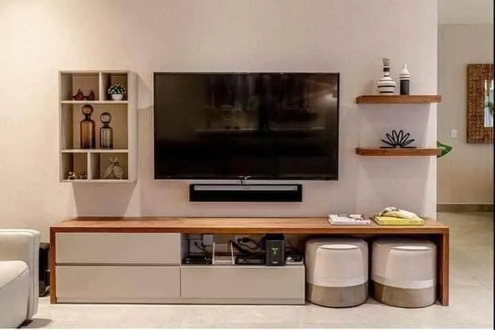Low, long TV console with a teak top and white drawer fronts, two ceramic drum stools pushed underneath it