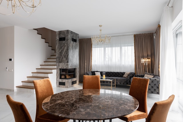 Open dining and living area with a round marble dining table, burnt-orange velvet chairs