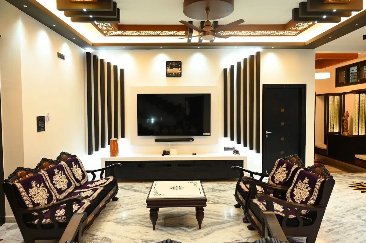 Living room with a coffered wood ceiling of lit jaali panels, a TV wall flanked by vertical black-and-wood fluted panelling